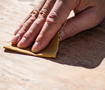 Schuren van het hout voor het schilderen met een kwast